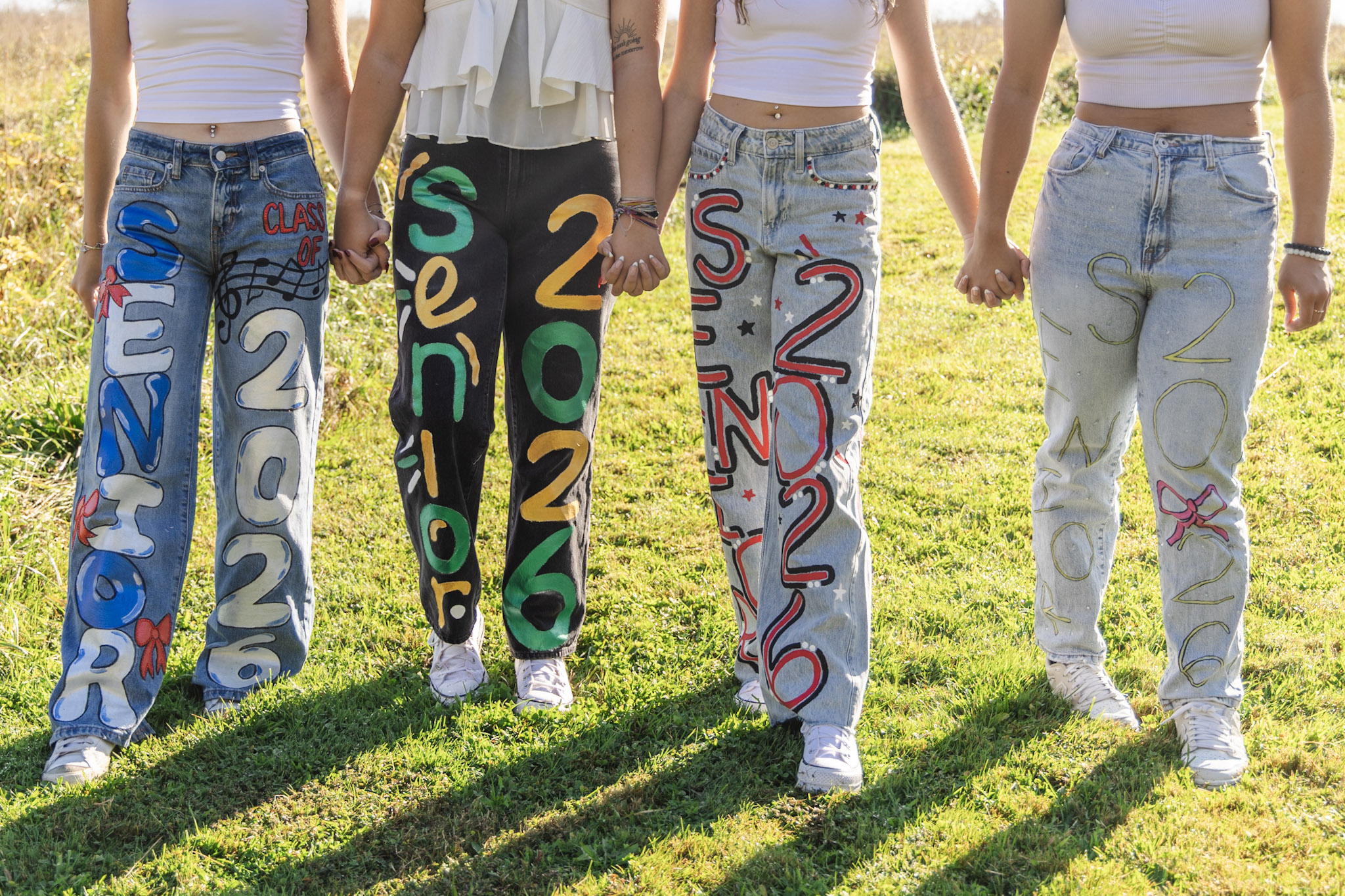 Senior friends holding hands in custom painted jeans